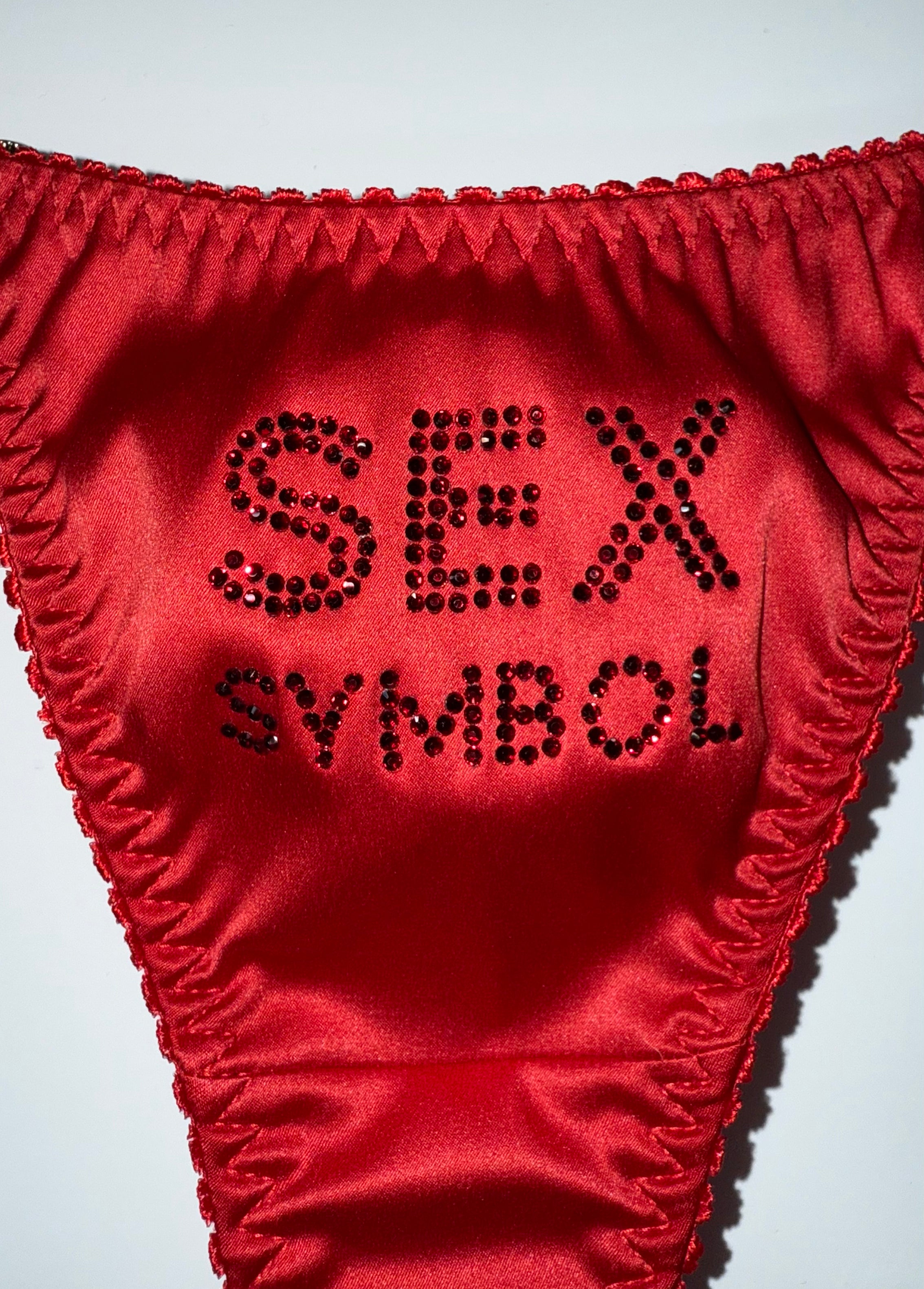 Червоні трусики з атласу з написом Sex Symbol зі страз.